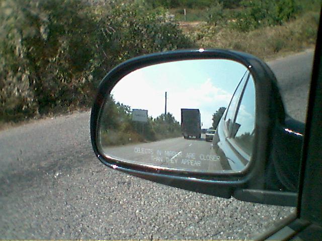In the rear-view-mirror the exit for the village is seen