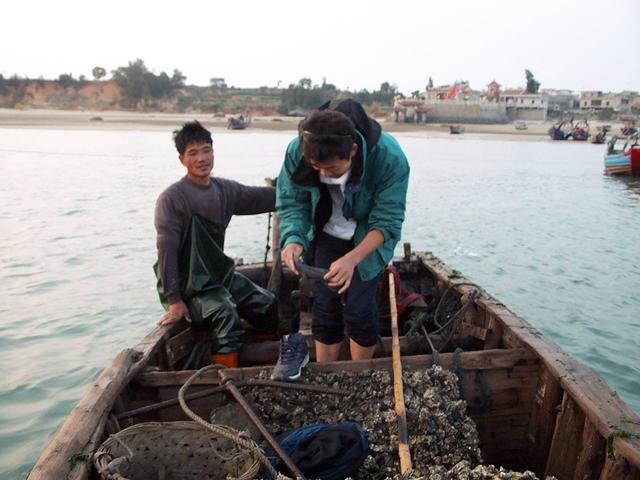 Getting into sea snail fishing boat with Mazu temple in back.