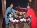 #3: Girls dressed in traditional Tujia minority nationality dress placing a large wok containing a bull's head at the centre of the table