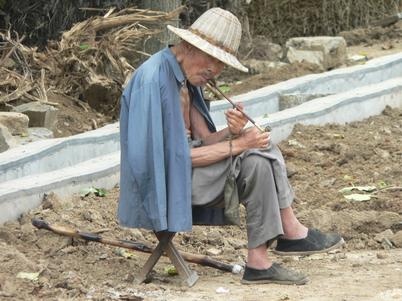 Old man smoking a long pipe