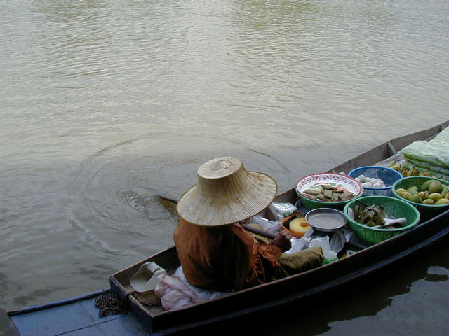 Elderly Thai woman selling produce from her boat along one of the many rivers near the confluence. Fresh fish, meat, and vegetables are abundant in the area.