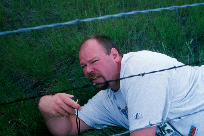 Curt crawling under the barbed wire fence.