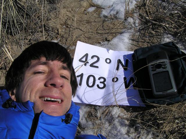 Joseph Kerski lying in the sand hills on the confluence of 42 North 103 West.