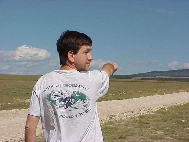 Joseph Kerski, clad in his "Without Geography, Where Would You Be?" shirt, points toward confluence from the southeast.