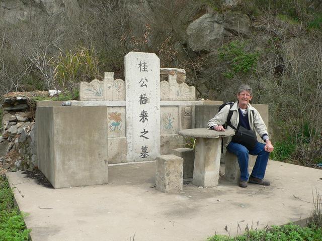 Jim sitting at the picnic table in front of a Chinese grave