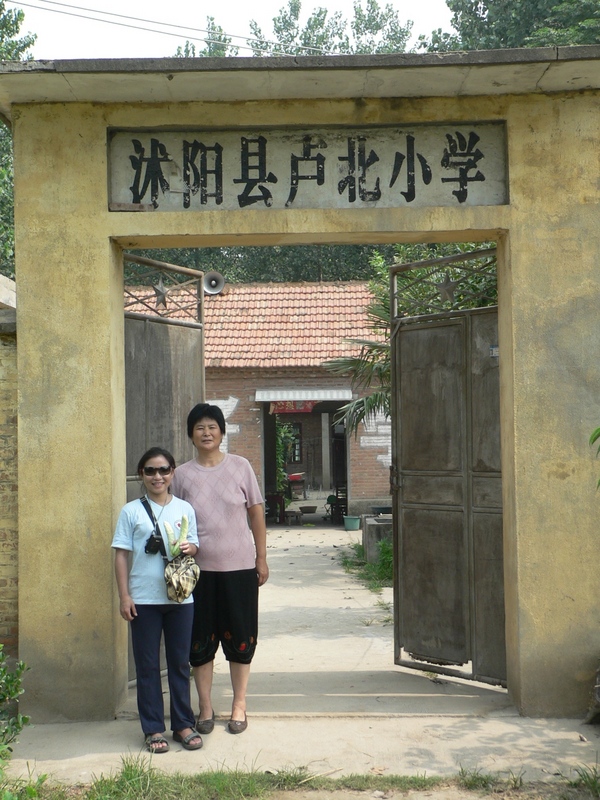 Ah Feng and Yáng Xiùhuá at the entrance to Lúběi Primary School