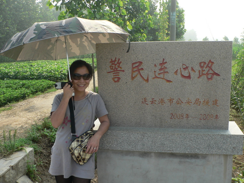 Ah Feng at the sign for Jǐngmín Liánxīn Road