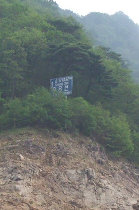Sign reading '38 Parallel' on a mountainside near the confluence.