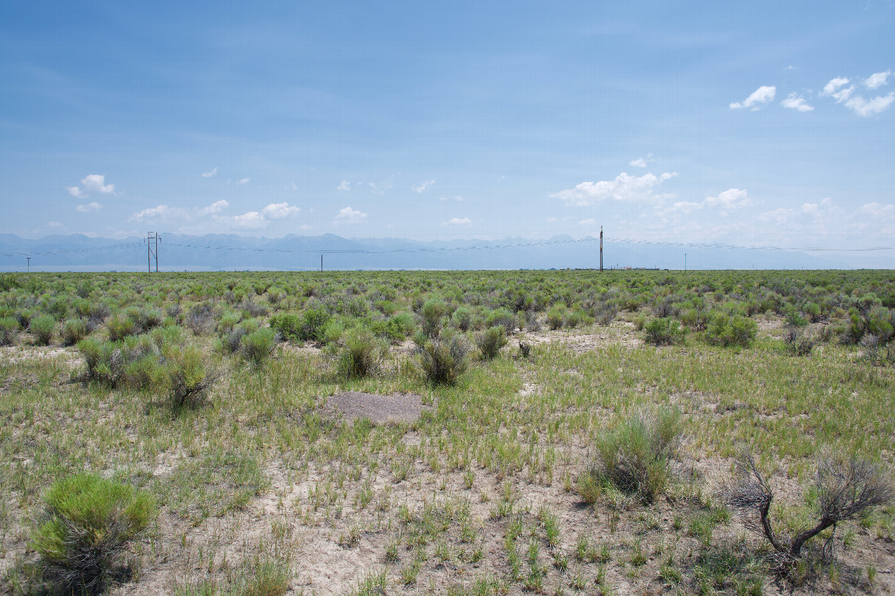The confluence point lies in flat, arid ranchland.  (This is also a view to the East, towards the Sangre de Cristo Mountains.)