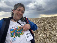 #3: Joseph Kerski at the confluence point, pointing at Iowa on map shirt. 