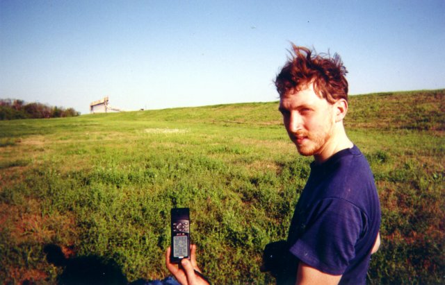 Alex holds the GPS, with a view to the east in the background.