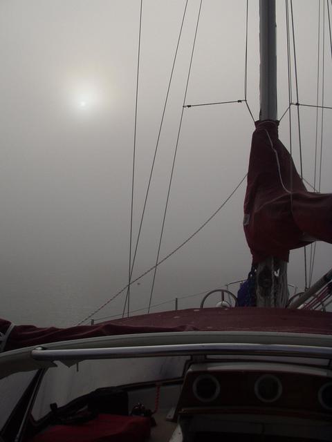 The sun peeks through the thick fog while underway