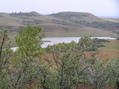 #2: View of the confluence from 500 meters to the northwest, looking southeast.  The confluence is on the far side of the reservoir, on top of the first bluf in center-right.
