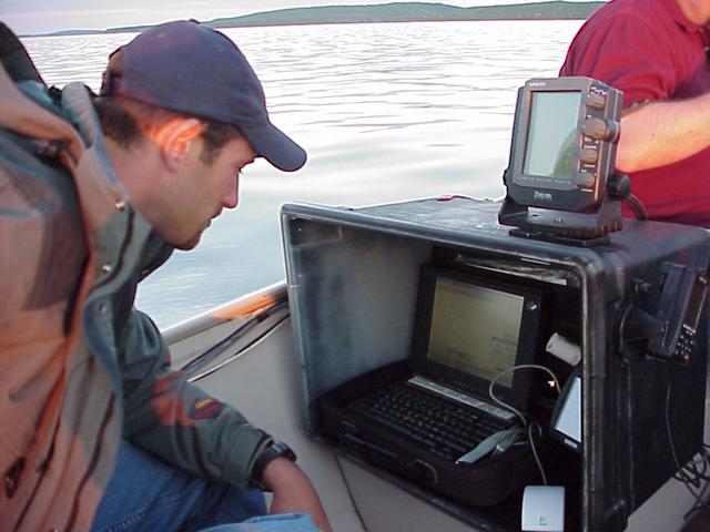 Ryan Krapp, left, monitors Trimble GPS and Garmin Sonar equipment used to map the floor of Devils Lake, North Dakota.