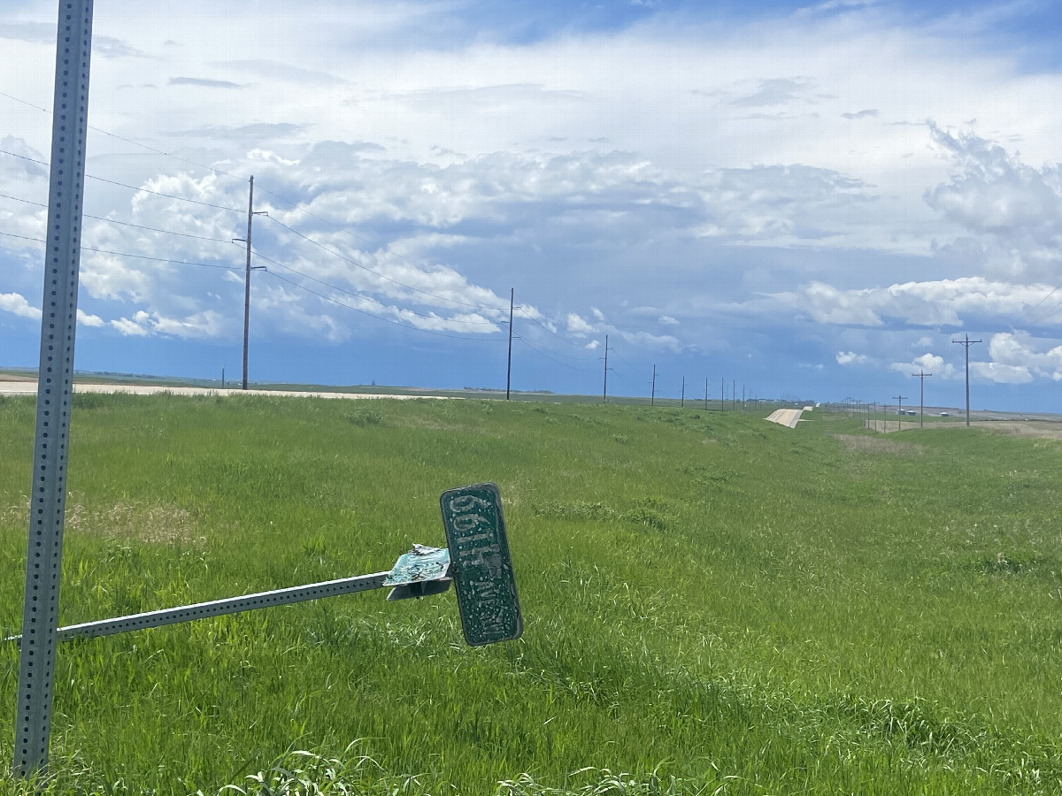 Road sign of the road leading to the confluence point looking at threatening thunderstorm toward my next destination. 