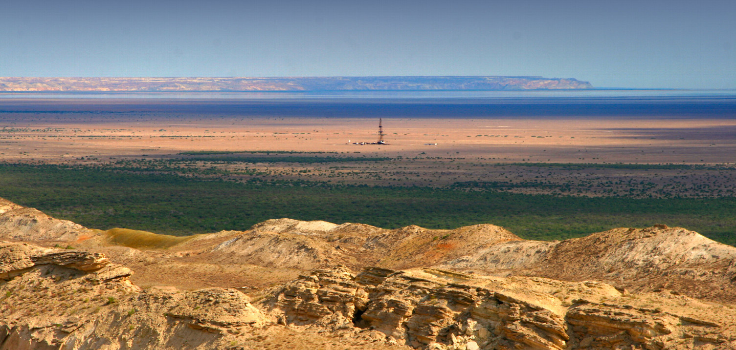 there once was water: drilling rig in front of leftover of Aral Sea and west escarpment called "Chink"