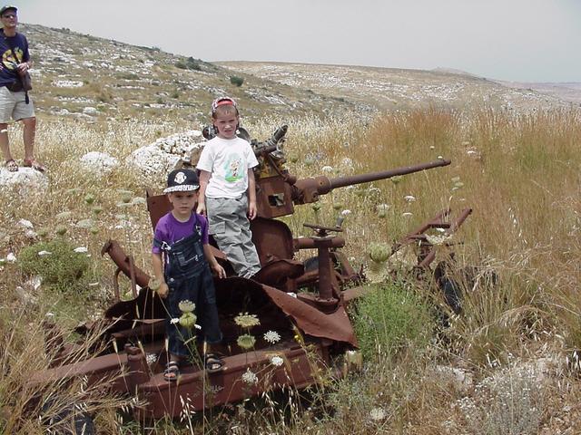 Tal and Omer sitting on an old cannon, Tsvika on the left
